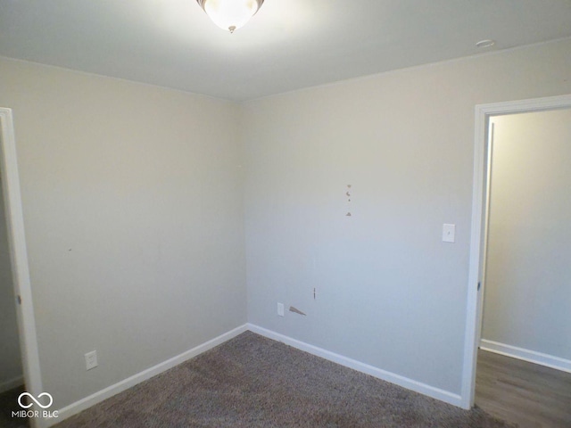 unfurnished room featuring baseboards and dark carpet