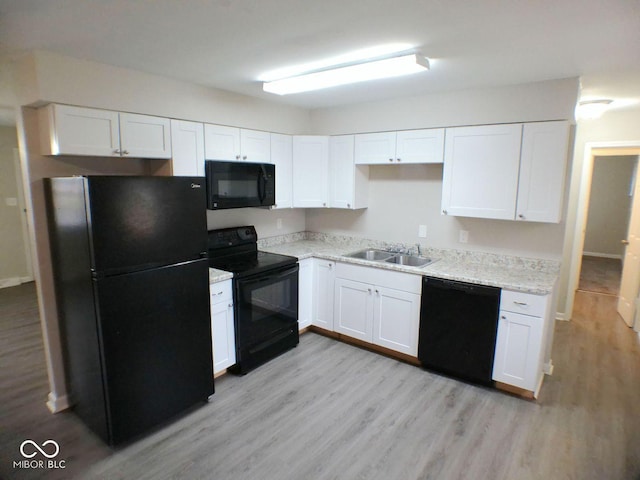 kitchen featuring white cabinetry, black appliances, light wood-type flooring, and a sink