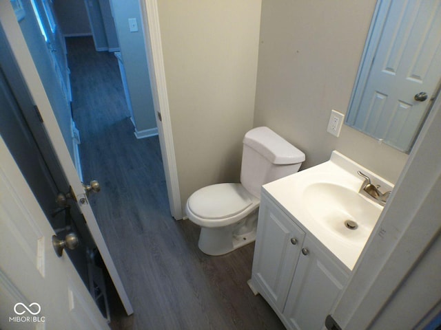 bathroom featuring vanity, toilet, wood finished floors, and baseboards