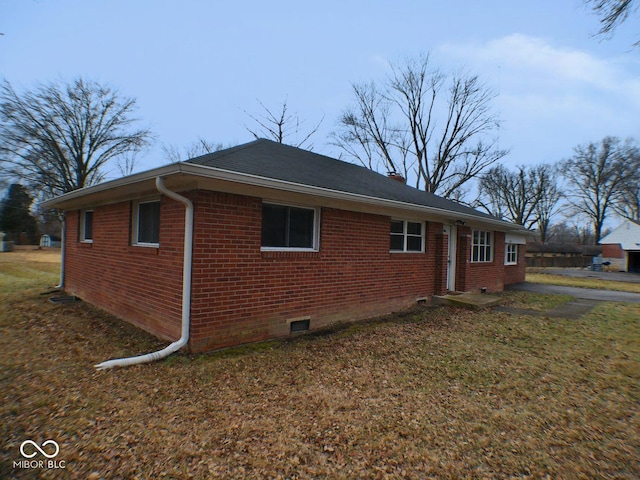 view of property exterior featuring crawl space, brick siding, and a yard