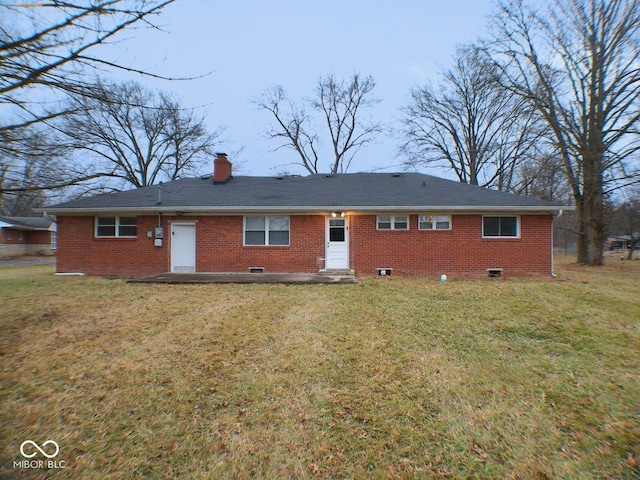 rear view of property with brick siding, a lawn, a chimney, and crawl space