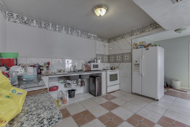 kitchen featuring light tile patterned floors, white appliances, tile walls, and a sink