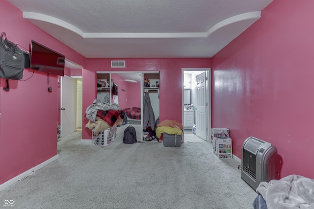 interior space featuring visible vents, a tray ceiling, a textured ceiling, ensuite bath, and baseboards