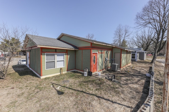 rear view of house featuring central air condition unit and roof with shingles