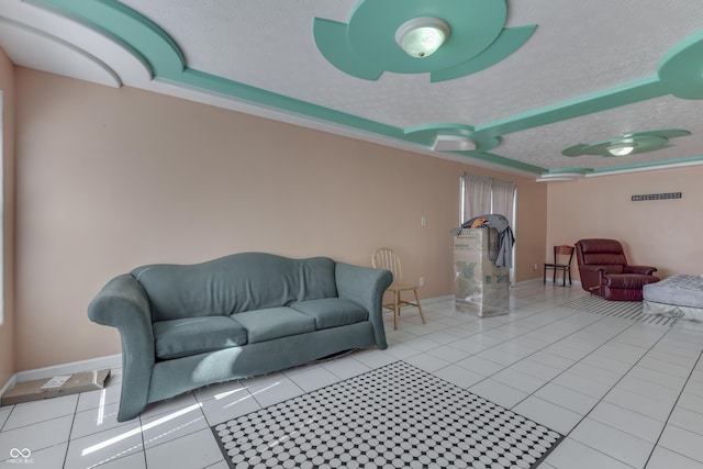 tiled living area featuring a textured ceiling, a raised ceiling, and baseboards