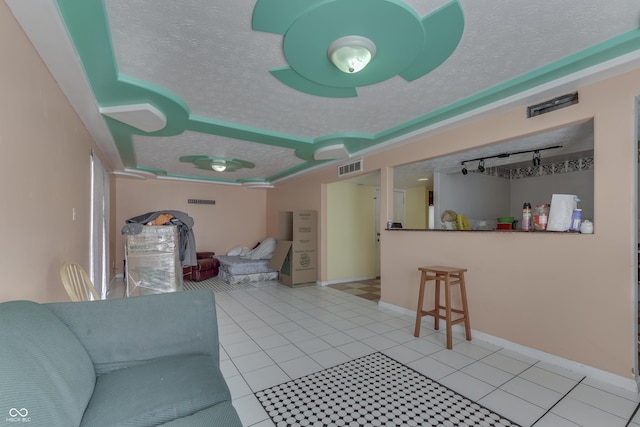 living room with light tile patterned floors, baseboards, visible vents, rail lighting, and a textured ceiling