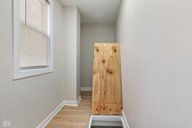 hallway featuring light wood finished floors and baseboards