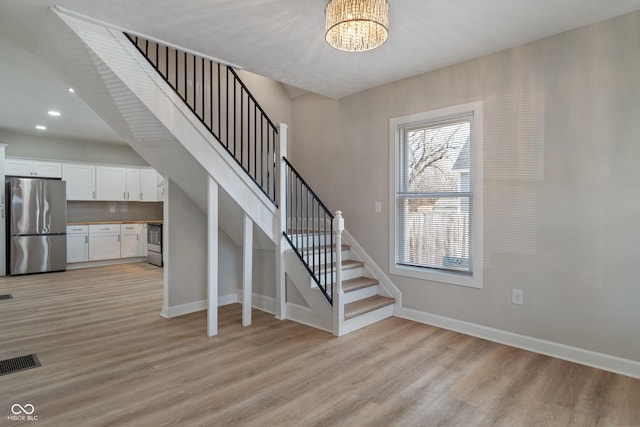 staircase with wood finished floors, visible vents, baseboards, an inviting chandelier, and recessed lighting