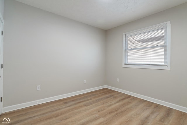 empty room featuring baseboards and light wood finished floors