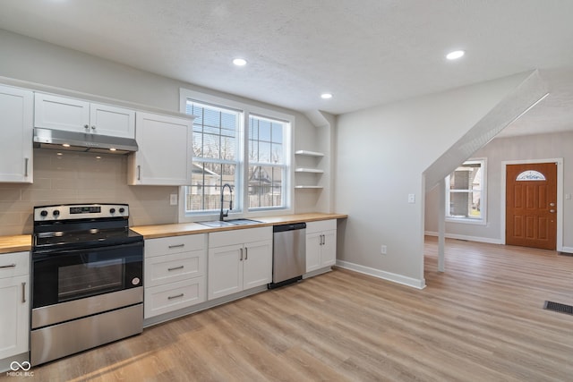 kitchen with visible vents, wooden counters, under cabinet range hood, appliances with stainless steel finishes, and a sink