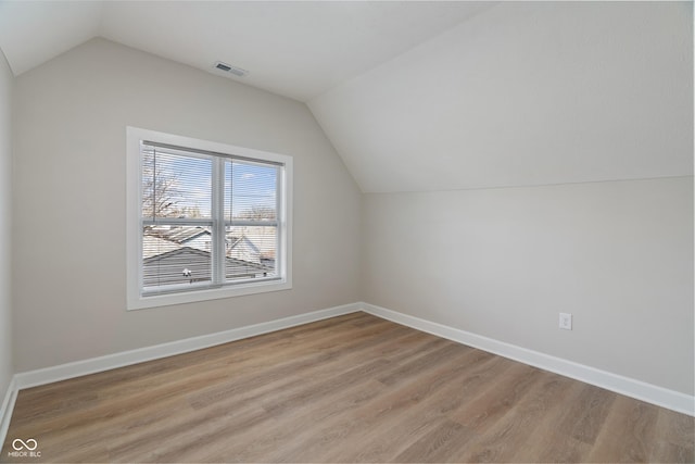 additional living space featuring visible vents, lofted ceiling, baseboards, and light wood finished floors