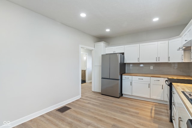 kitchen featuring visible vents, black electric range oven, tasteful backsplash, freestanding refrigerator, and wooden counters