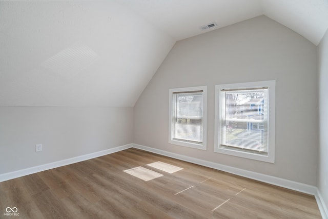 bonus room with wood finished floors, baseboards, visible vents, and vaulted ceiling