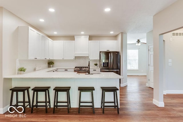 kitchen with visible vents, appliances with stainless steel finishes, a peninsula, wood finished floors, and a sink