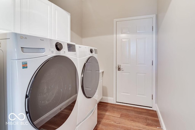 washroom featuring washer and dryer, light wood-type flooring, cabinet space, and baseboards