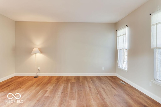 spare room featuring visible vents, light wood-type flooring, and baseboards