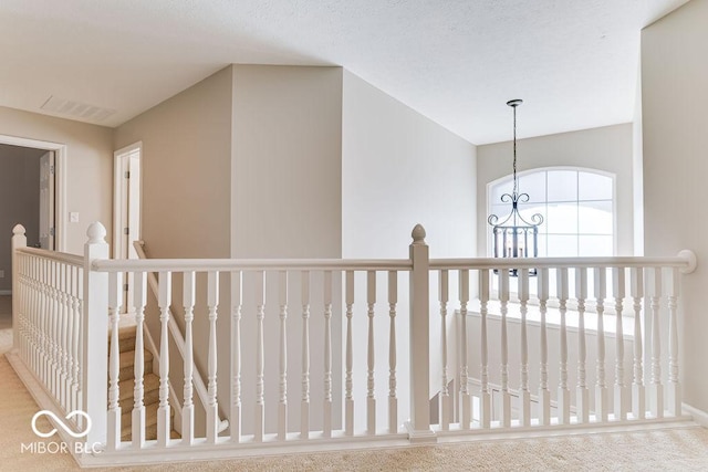 hall with an inviting chandelier, an upstairs landing, and visible vents