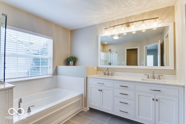 bathroom with tile patterned floors, a bath, a stall shower, and a sink