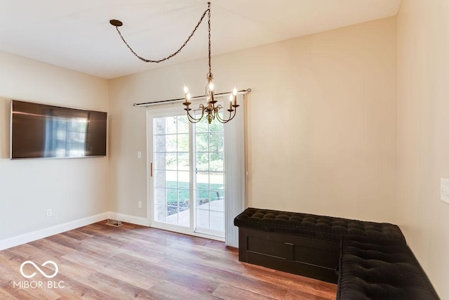 interior space featuring a notable chandelier, wood finished floors, and baseboards