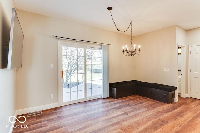 unfurnished dining area featuring an inviting chandelier, baseboards, visible vents, and light wood-type flooring