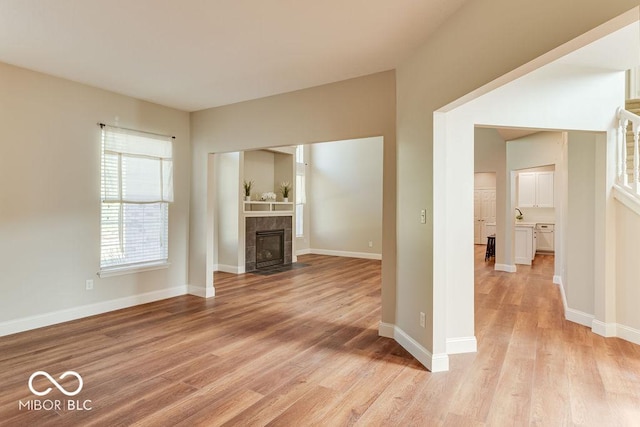 unfurnished living room featuring light wood-style flooring, a fireplace, and baseboards