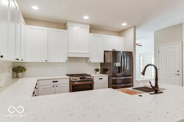 kitchen featuring tasteful backsplash, appliances with stainless steel finishes, light stone counters, and a sink