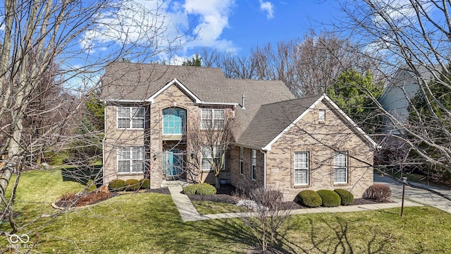 traditional-style home with a front lawn, brick siding, and a shingled roof