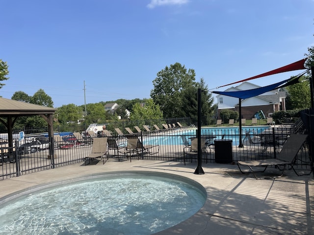 community pool featuring a patio, a jacuzzi, and fence