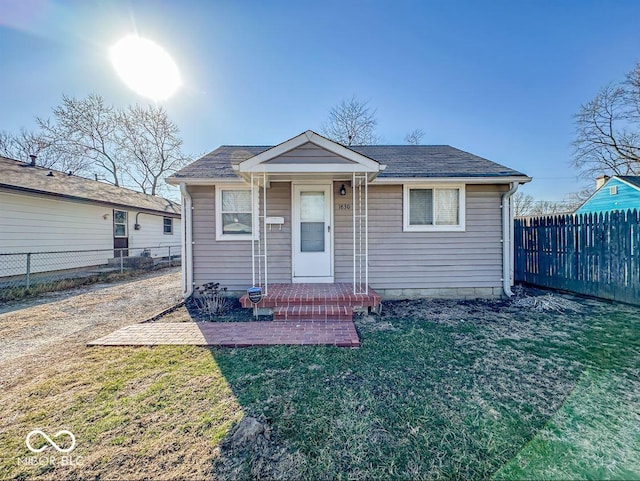 bungalow with a porch, a front lawn, and fence