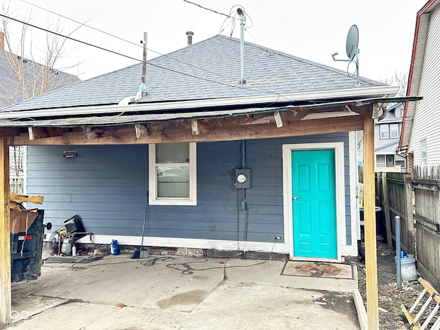 rear view of property featuring roof with shingles and fence