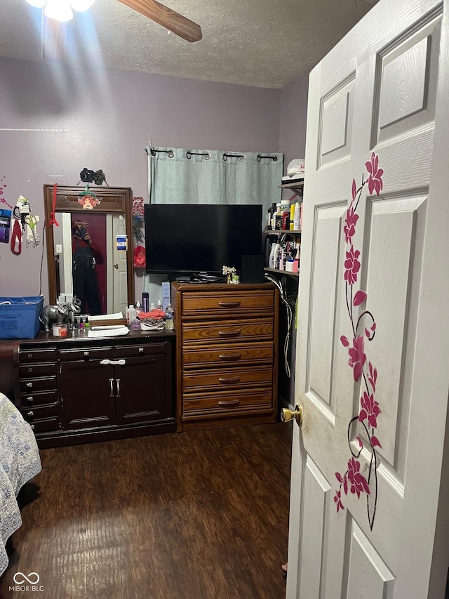 bedroom with a ceiling fan, dark wood-style flooring, and a textured ceiling