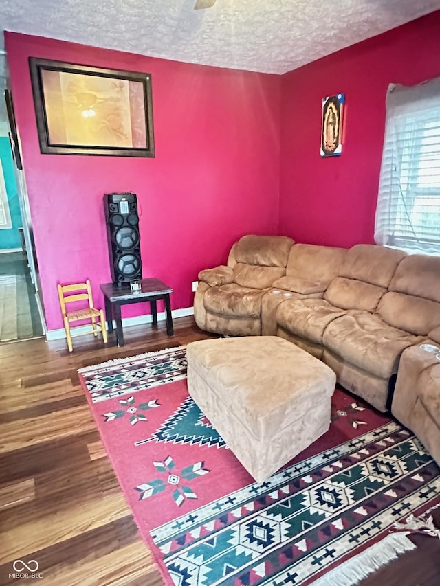 living room with baseboards, a textured ceiling, and wood finished floors