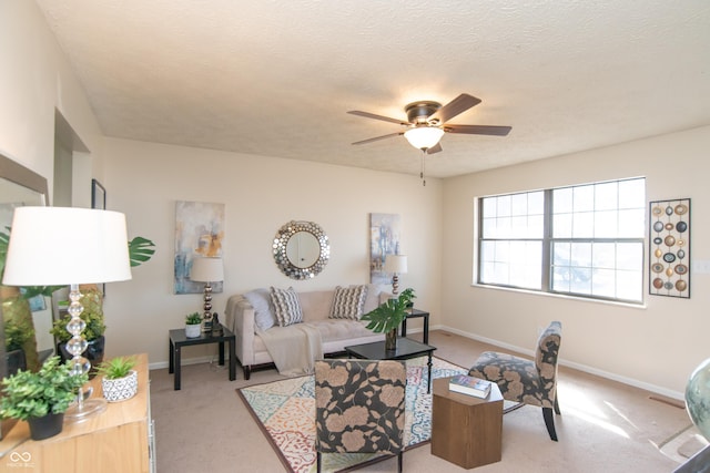 living room with baseboards, light carpet, a textured ceiling, and a ceiling fan