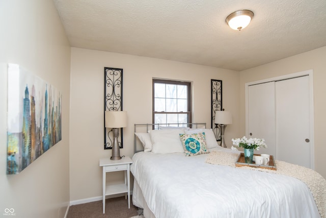 carpeted bedroom with a closet, a textured ceiling, and baseboards