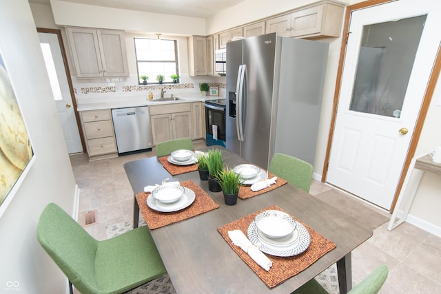 kitchen with baseboards, a sink, light countertops, appliances with stainless steel finishes, and backsplash