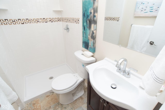 full bathroom with vanity, toilet, and a tile shower