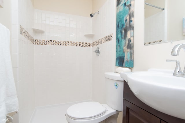 bathroom with vanity, toilet, and a tile shower