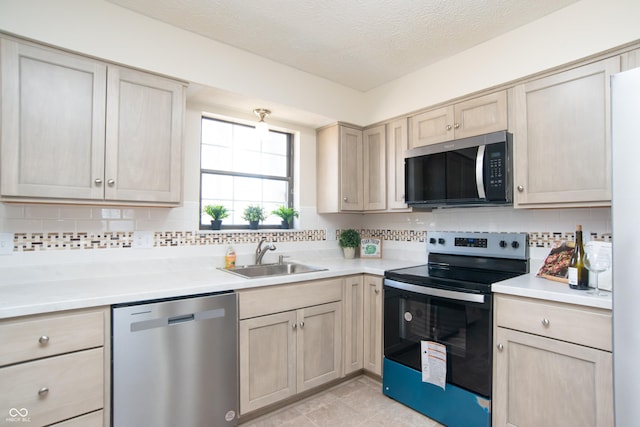 kitchen with a sink, decorative backsplash, light countertops, and stainless steel appliances