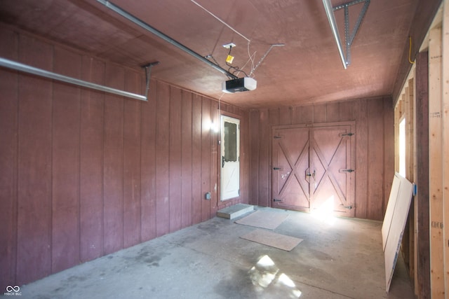 garage with wood walls and a garage door opener