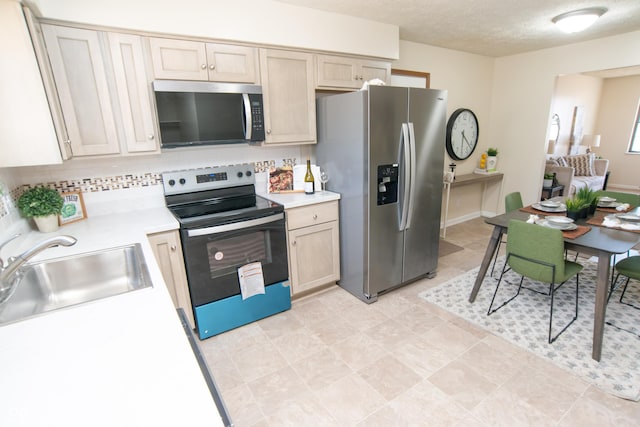 kitchen with a sink, stainless steel appliances, light countertops, a textured ceiling, and tasteful backsplash