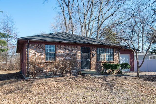 ranch-style home featuring brick siding, entry steps, a garage, and fence