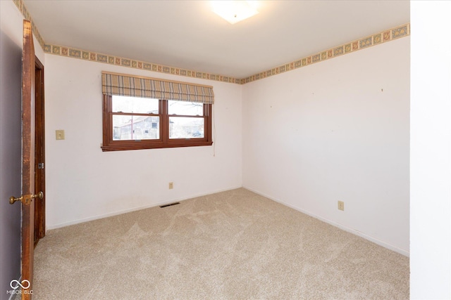 spare room featuring carpet flooring, baseboards, and visible vents