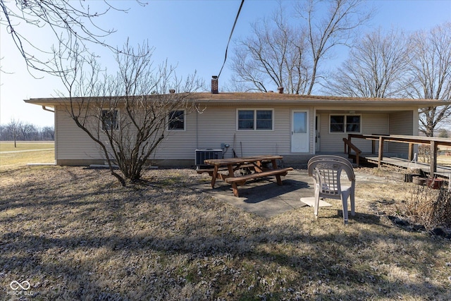 back of house featuring central air condition unit, a wooden deck, and a chimney