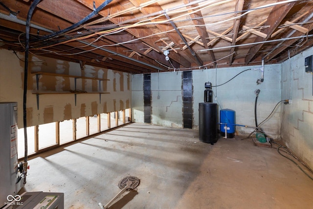 unfinished basement featuring concrete block wall and water heater