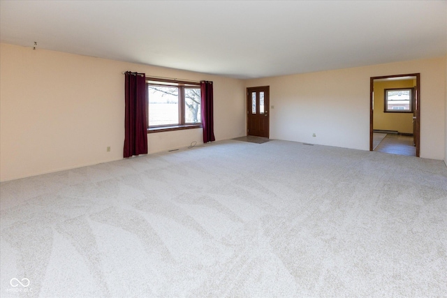 unfurnished room featuring a baseboard radiator, a wealth of natural light, and light carpet