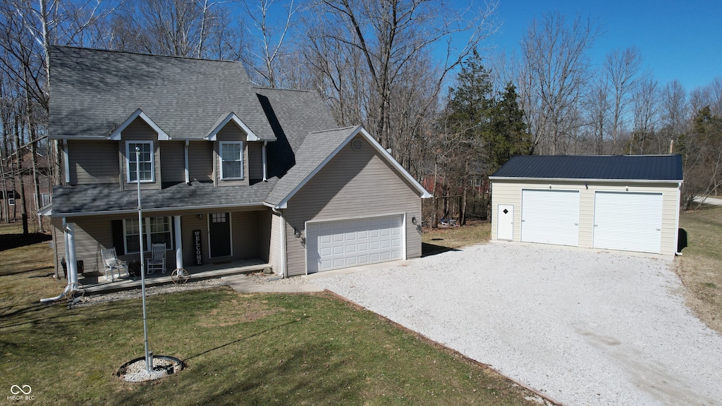 traditional-style home featuring a garage, covered porch, a front yard, and a shingled roof