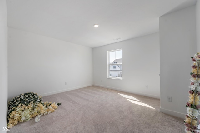 carpeted spare room with visible vents and baseboards