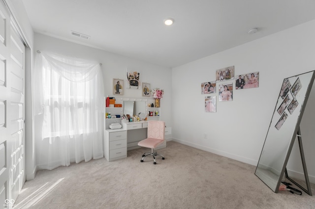 office with baseboards, visible vents, and light carpet