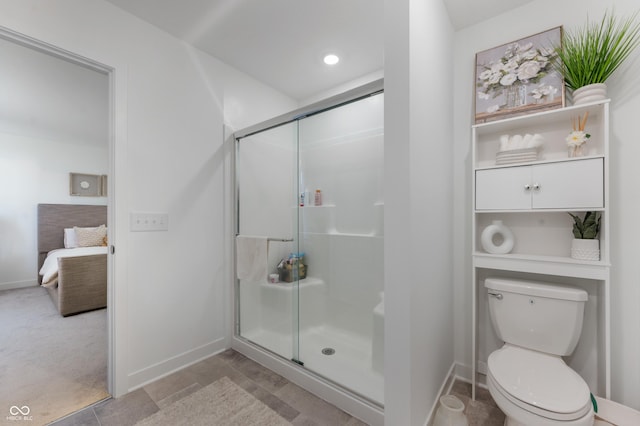 ensuite bathroom featuring baseboards, ensuite bathroom, toilet, and a shower stall