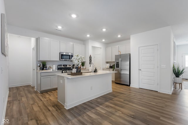 kitchen featuring dark wood finished floors, an island with sink, recessed lighting, stainless steel appliances, and a sink